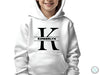 a young boy wearing a white hoodie with the letter k on it