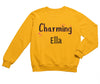 a little girl wearing a yellow sweatshirt that says charming ella